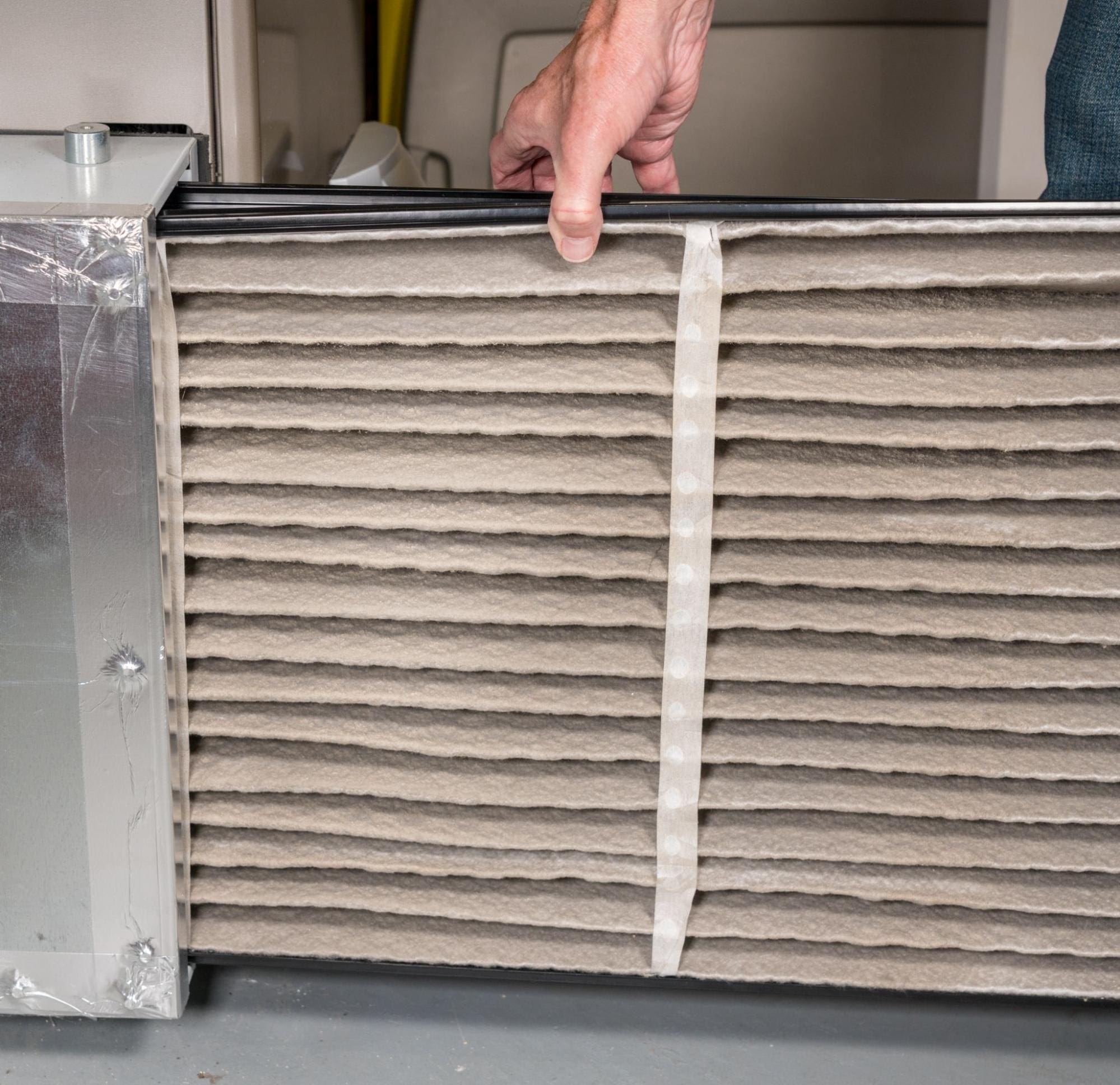 Man changing a dirty air filter in a HVAC furnace 